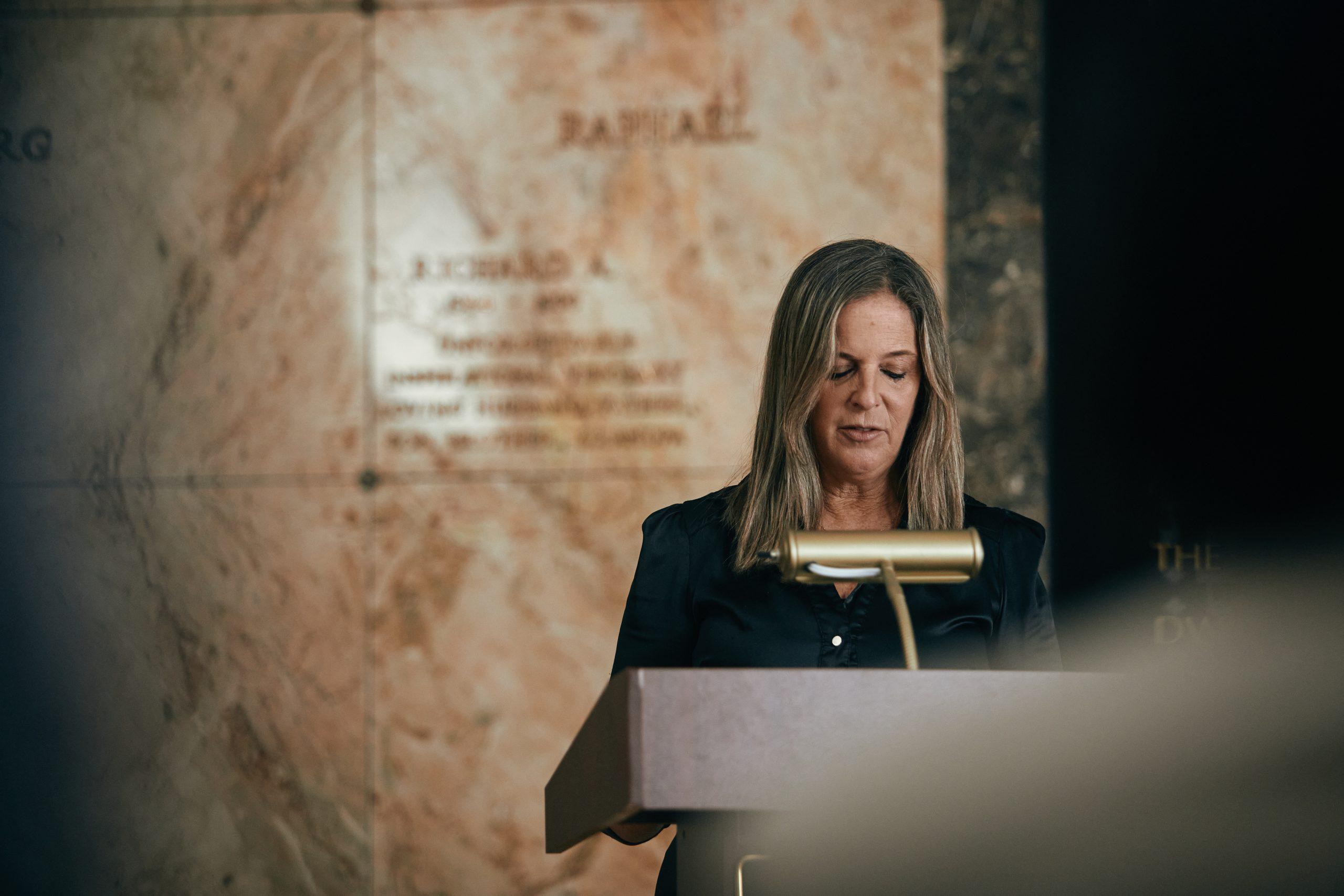 Rabbi Jessica Spitalnic Mates at the podium during a funeral at the Beth El Mausoleum